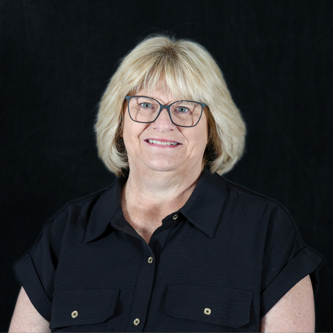 Woman smiling with glasses in front of a black background. 